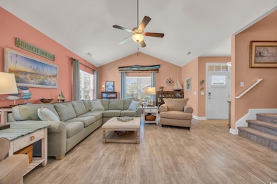 Spacious Living area with light wood-style flooring, a ceiling fan, vaulted ceiling, baseboards, and stairway to upstairs to the left.
