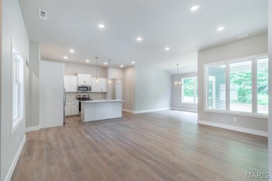 Kitchen featuring open floor plan, recessed lighting, light countertops, white cabinets, and a kitchen island with sink