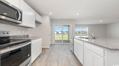 Kitchen with white cabinets, sink, light stone cou
