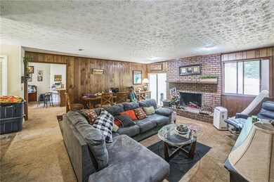 Carpeted living room with plenty of natural light, wood walls, a fireplace, and a textured ceiling