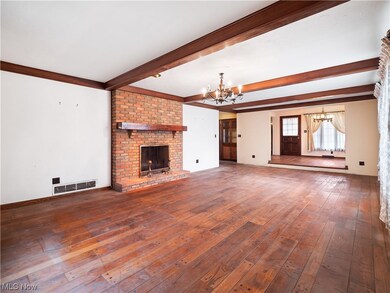 Unfurnished living room with dark hardwood / wood-style flooring, a notable chandelier, a fireplace, and brick wall