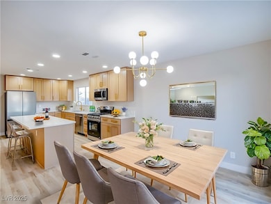 Dining room with light wood-style floors, a chandelier, and recessed lighting