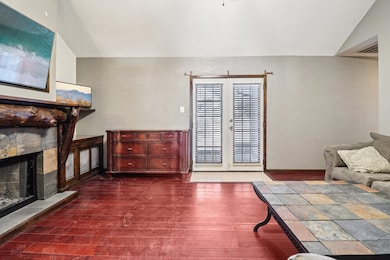 Living area featuring lofted ceiling, a fireplace, dark wood-type flooring, and french doors