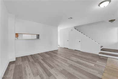 Unfurnished living room featuring stairs, wood fin