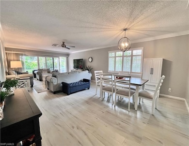Dining area with a textured ceiling, healthy amount of natural light, light wood plank style tile flooring, ornamental molding, and a chandelier