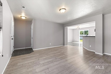 Unfurnished living room with wood finished floors, a textured ceiling, and a chandelier