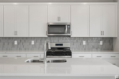 Kitchen with a sink, white cabinetry, appliances with stainless steel finishes, and tasteful backsplash