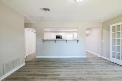 Unfurnished living room with baseboards, visible vents, and wood finished floors