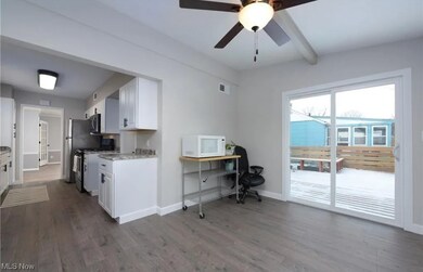 Kitchen featuring ceiling fan, light stone counters, dark hardwood floors and white cabinets.