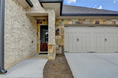 Entrance to property with a shingled roof, stone siding, brick siding, and an attached garage