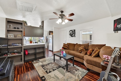 Living area with dark wood-type flooring, a ceiling fan, and a textured ceiling