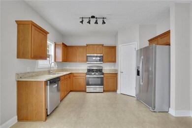 Kitchen with appliances with stainless steel finishes, light stone counters, and brown cabinetry