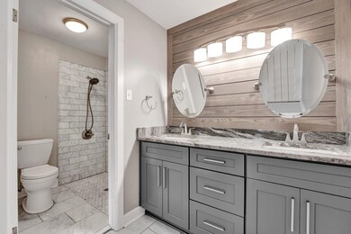 Bathroom with toilet, wood walls, vanity, and a ti