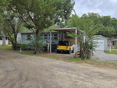 Manufactured / mobile home with a detached carport, driveway, and an outdoor structure