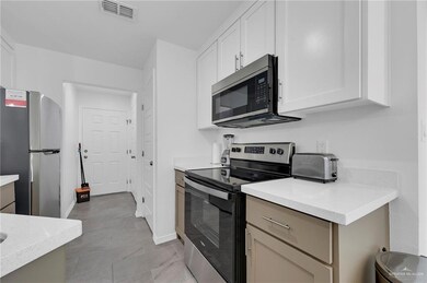 Kitchen featuring stainless steel appliances, light countertops, white cabinets, and baseboards