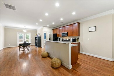 Kitchen featuring ornamental molding, an island with sink, recessed lighting, appliances with stainless steel finishes, and light wood-style flooring