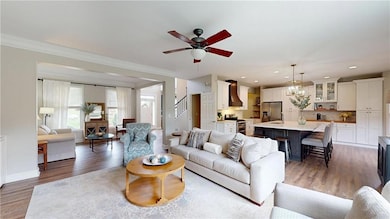 Living room featuring a ceiling fan, ornamental molding, wood finished floors, recessed lighting, and baseboards