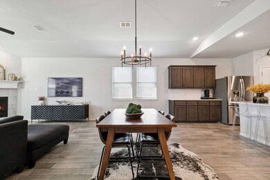 Dining space with a notable chandelier, vaulted ceiling, light hardwood / wood-style floors, and a tile fireplace