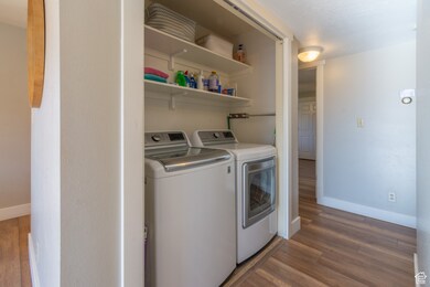 Laundry area with dark wood-style floors and washer and clothes dryer