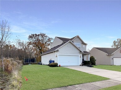 View of side of home featuring a lawn, a trampoline, driveway, a shingled roof, and an attached garage