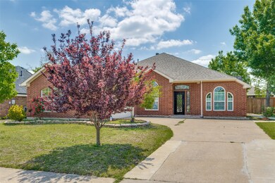 View of front facade featuring brick siding, driveway, a front yard, and fence