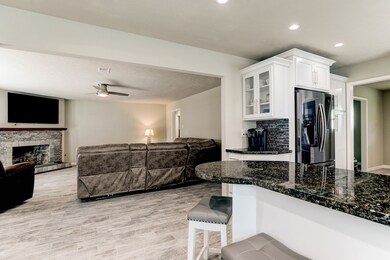 View from the breakfast nook looking out into the family room.  Custom made coffee bar located just to the left of the black stainless fridge. Amazing see though shelving is another upgrade in this functional and stylish kitchen.  The breakfast bar is located just off the breakfast nook area.