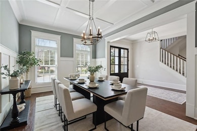 Dining space featuring a wainscoted wall, coffered ceiling, beamed ceiling, and wood finished floors
