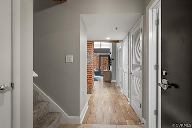 Hall featuring brick wall and light wood-type floo