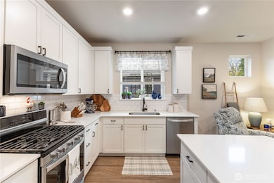 The open kitchen and has stainless appliances, gas stove, quartz counters, tile backsplash and tons of counter and cupboard space.