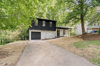 Split level home featuring stone siding, concrete driveway, and an attached garage