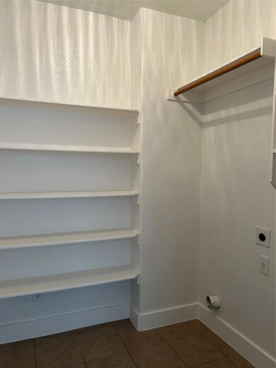 Washroom with electric dryer hookup and dark tile