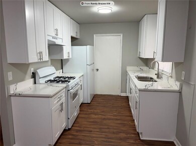 Brand new white and bright kitchen. Soft close cabinets/drawers and crisp, modern quartz countertops give this home a modern facelift. The door opens to a den and workshop and also access to the rear yard and patio.