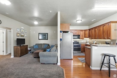 Kitchen with stainless steel appliances, a peninsula, open floor plan, a kitchen breakfast bar, and light wood finished floors