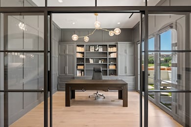 The front office is enclosed in glass with built-in cabinetry and sleek wall paneling that gives the space a polished, professional feel. With double doors leading out to the gated patio, it’s a workspace that offers both privacy and a quiet place to step out for a break