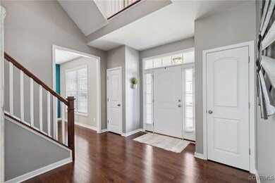 Foyer with lofted ceiling and dark hardwood / wood