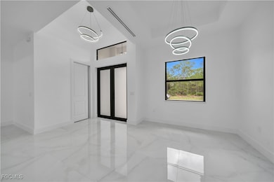 Empty room featuring light marble finish flooring, a towering ceiling, french doors, and a chandelier