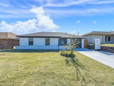 Single story home with a front lawn, roof with shingles, driveway, and concrete block siding