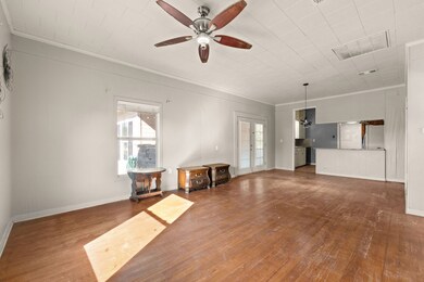Unfurnished living room with crown molding, dark wood-style flooring, and ceiling fan