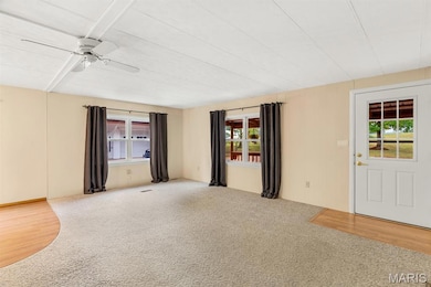 Carpeted empty room with healthy amount of natural light, a ceiling fan, and wood finished floors