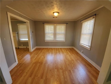 Unfurnished dining area with crown molding, light wood-style floors, and baseboards