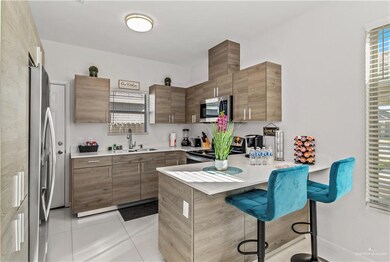 Kitchen with appliances with stainless steel finishes, a kitchen bar, sink, and light tile patterned floors