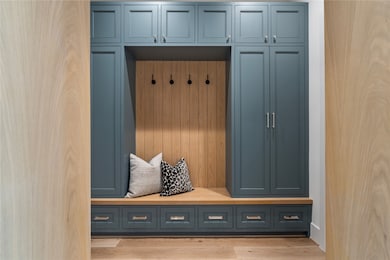 The mud room between the garage and main living area houses a tongue & groove white oak bench, great for taking off boots or lacing up sneakers. Floor-to-ceiling cabinetry will house outwear, sports gear, and more with ease. The dark blue tones complement the oak nicely.