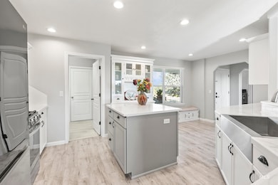 Kitchen with white cabinetry, gray cabinets, arched walkways, glass insert cabinets, and recessed lighting