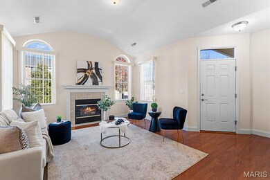 Living area featuring dark wood-style flooring, vaulted ceiling, and a fireplace