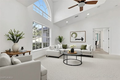 Living room featuring light carpet, a towering ceiling, healthy amount of natural light, ceiling fan, and recessed lighting
