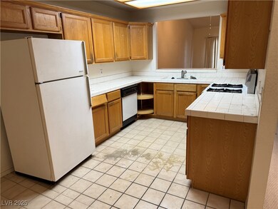 Kitchen with brown cabinetry, white appliances, ti