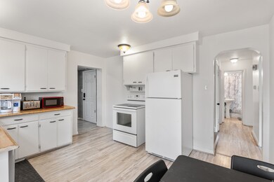 Kitchen with white appliances, arched walkways, light countertops, and white cabinetry