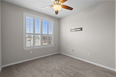 Primary bedroom with ceiling fan and neutral walls