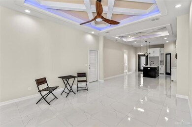 Living area with ceiling fan, beam ceiling, coffered ceiling, and light tile floors