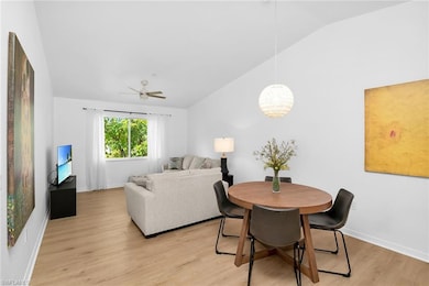 Dining room featuring vaulted ceiling, light wood finished floors, baseboards, a ceiling fan, and a chandelier